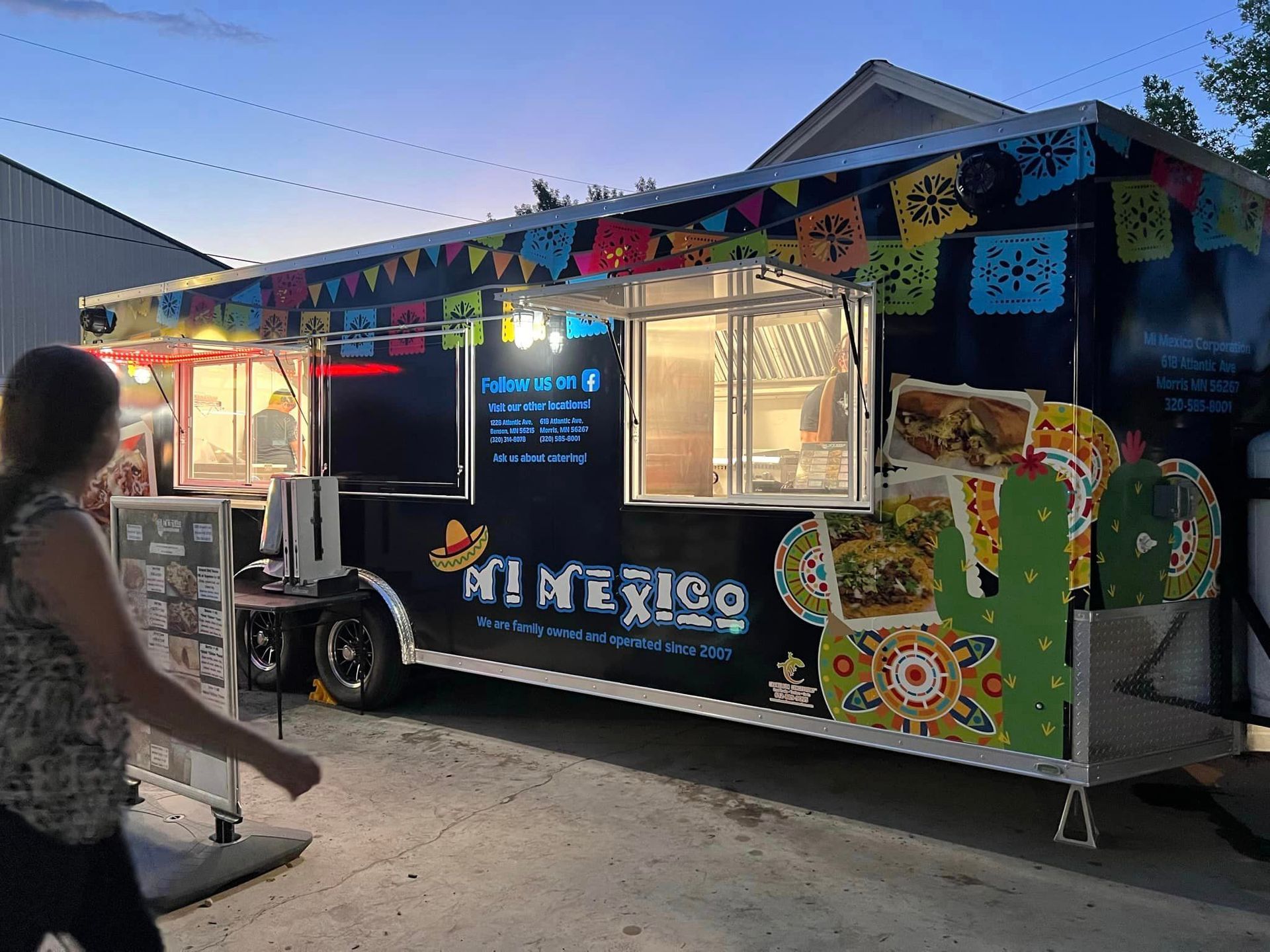 A woman is walking past a mexican food truck.