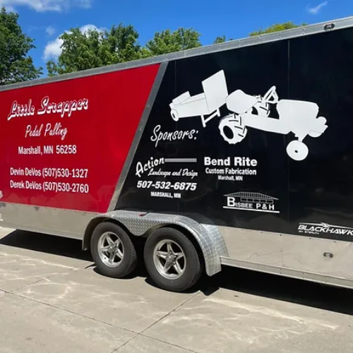 A red and black trailer is parked on the side of the road