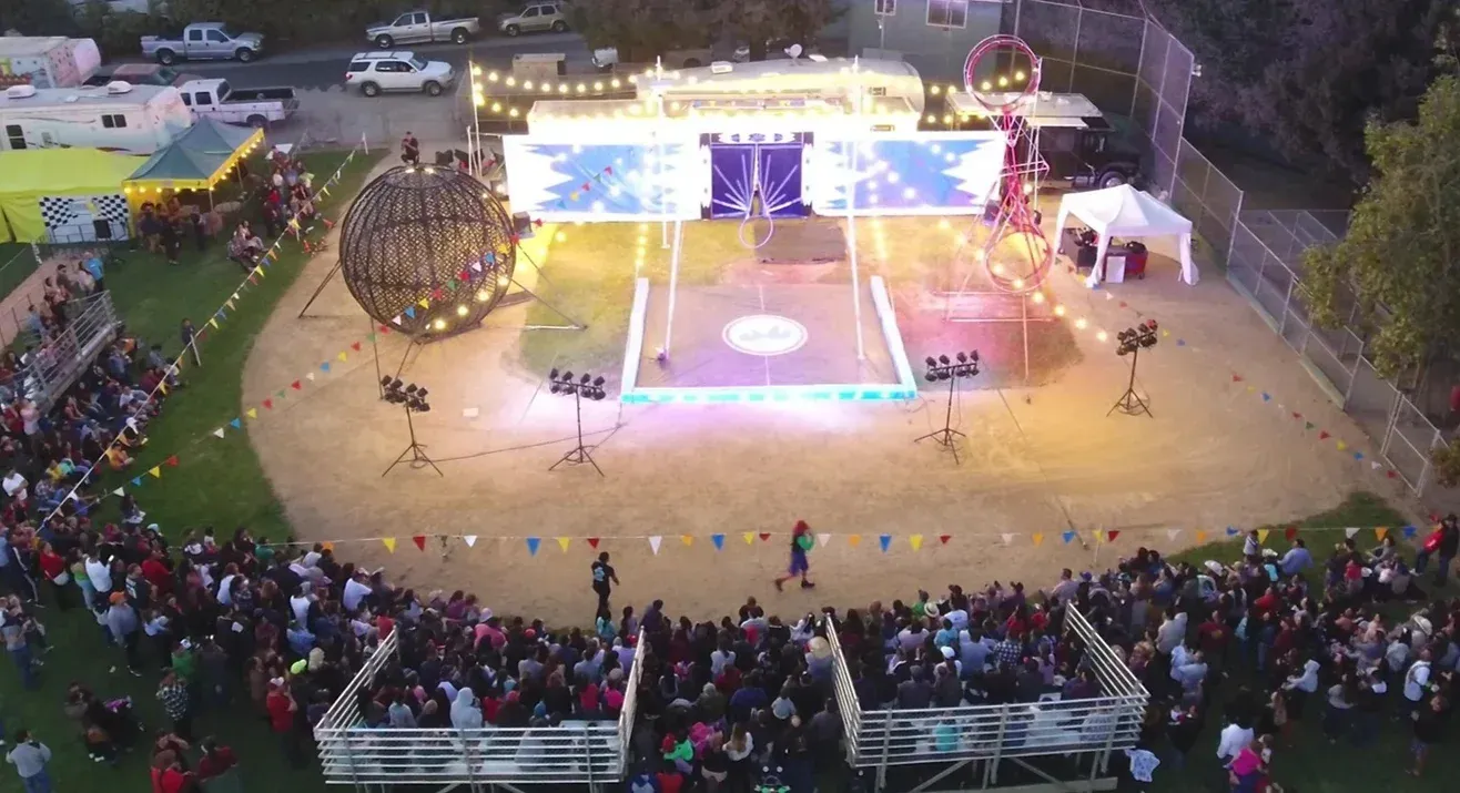 A white chicken with a red crest is standing in a cage.