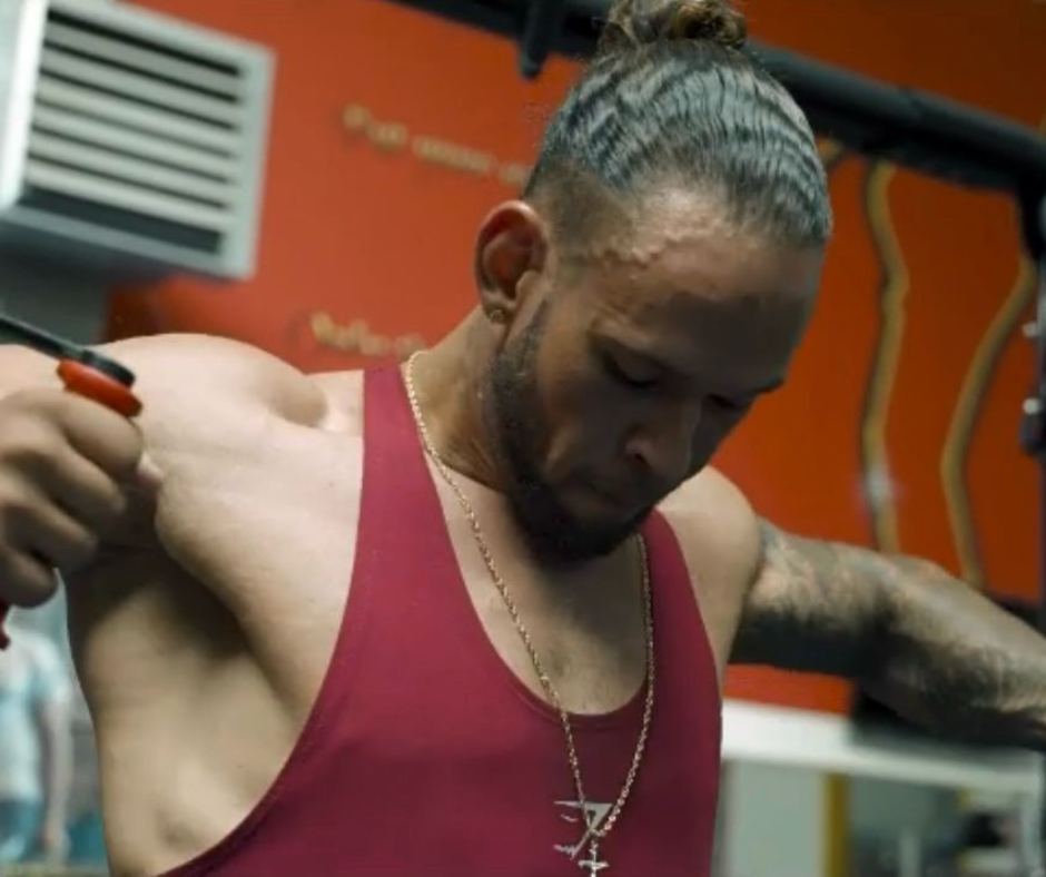 Een man die een rode tanktop draagt ​​met een kruis erop