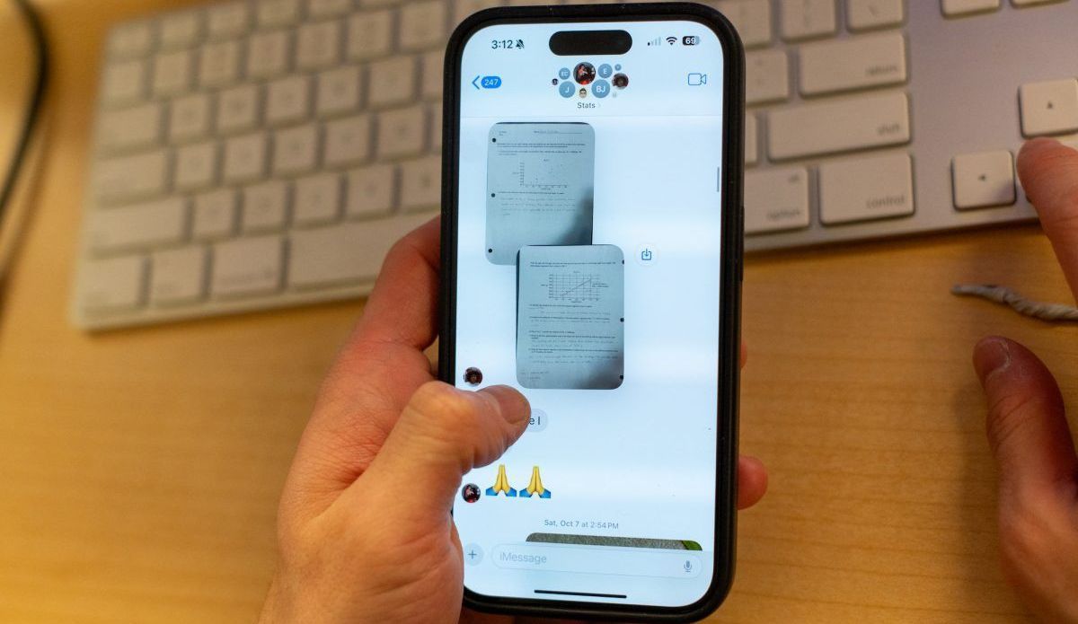 Hand holding iPhone, displaying two superimposed text message screenshots. Keyboard in background.