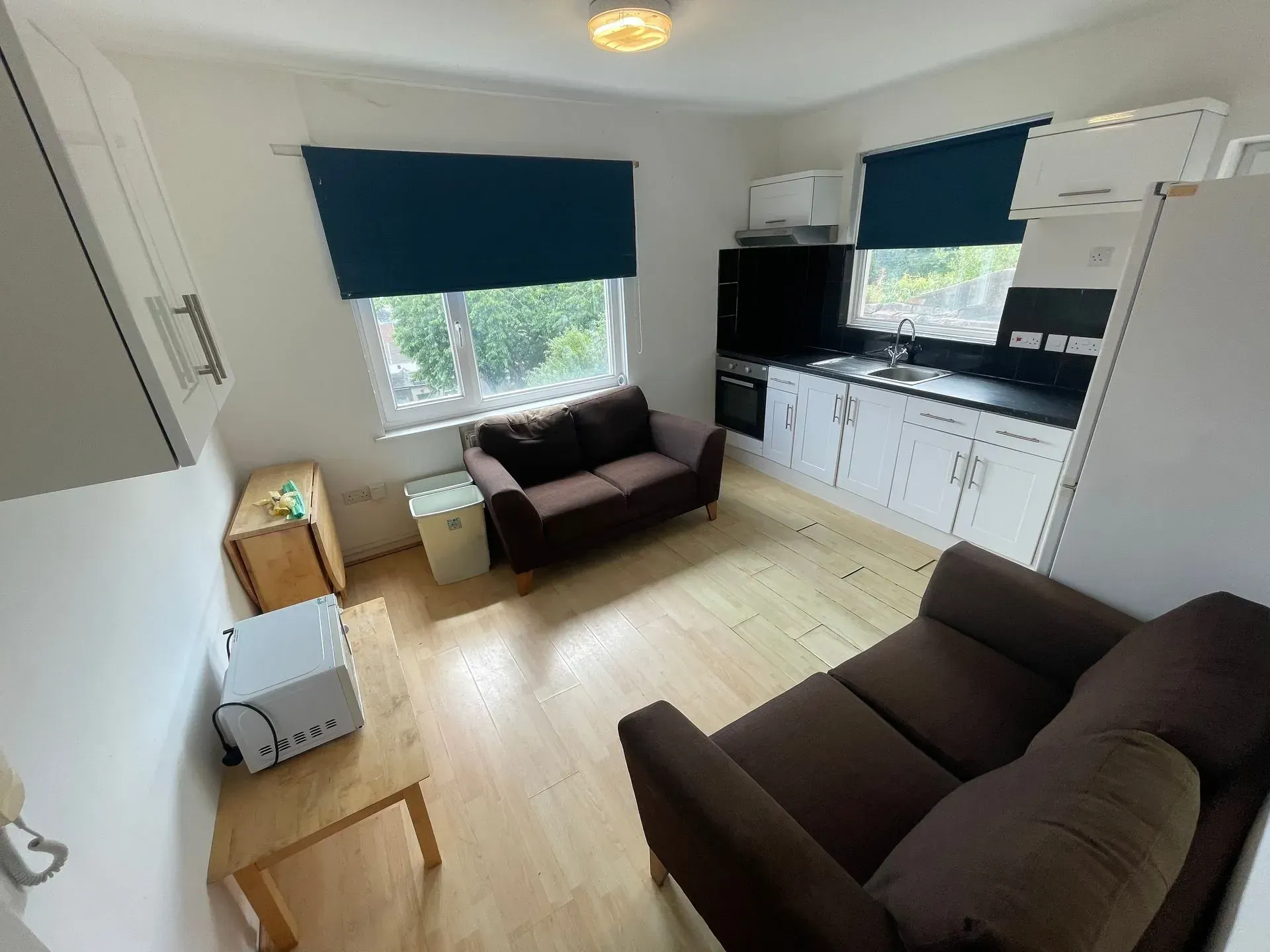 Small apartment with brown sofas, white cabinets, and a window.