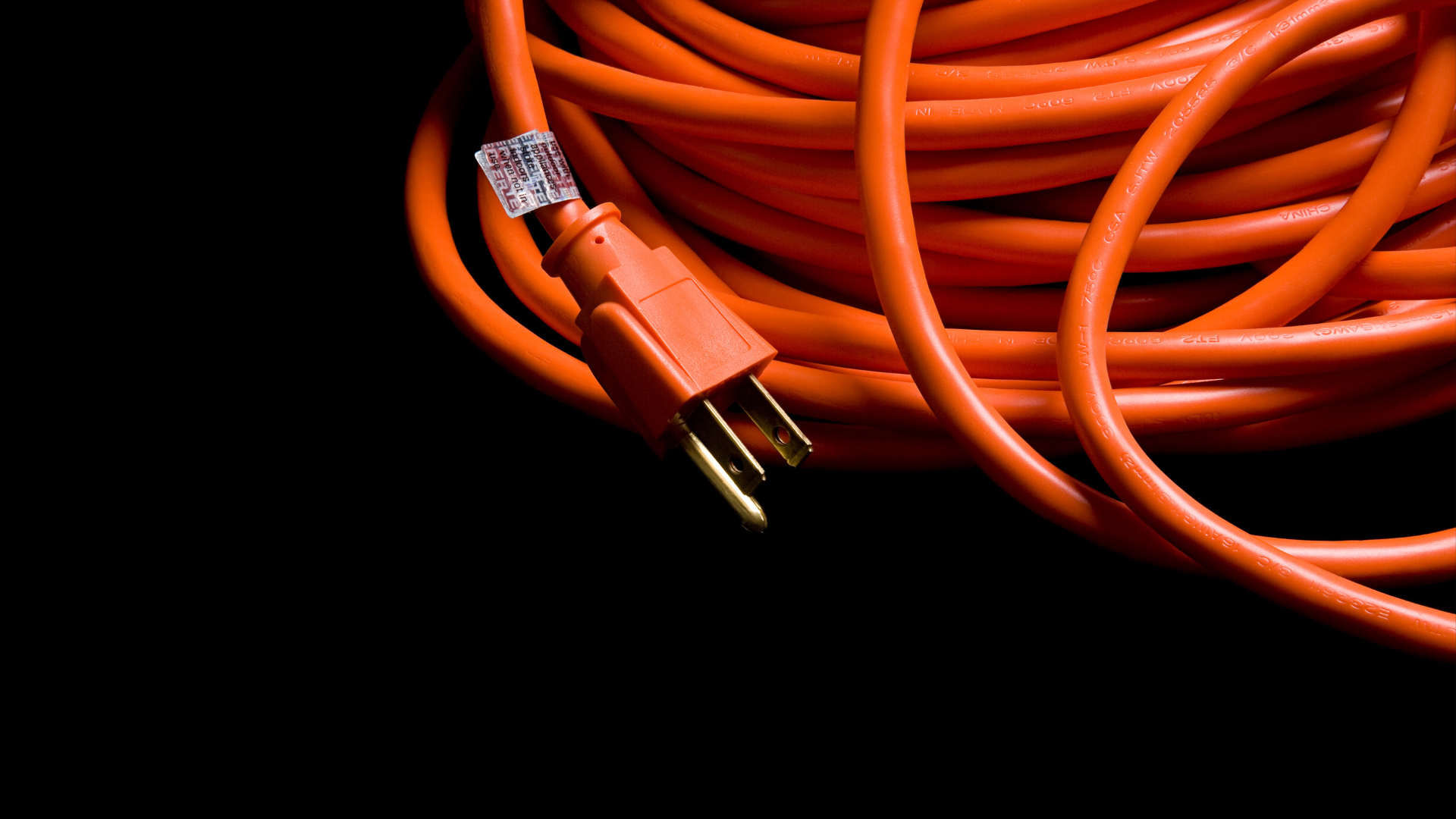 A close up of an orange extension cord on a black background