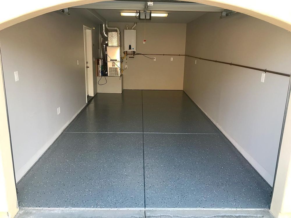 Empty garage interior with epoxy floor, light gray walls, and equipment.