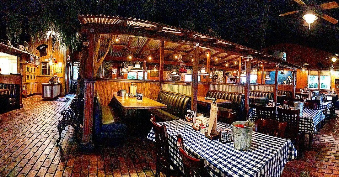 Restaurant interior with wooden structures, tables, and benches under string lights.