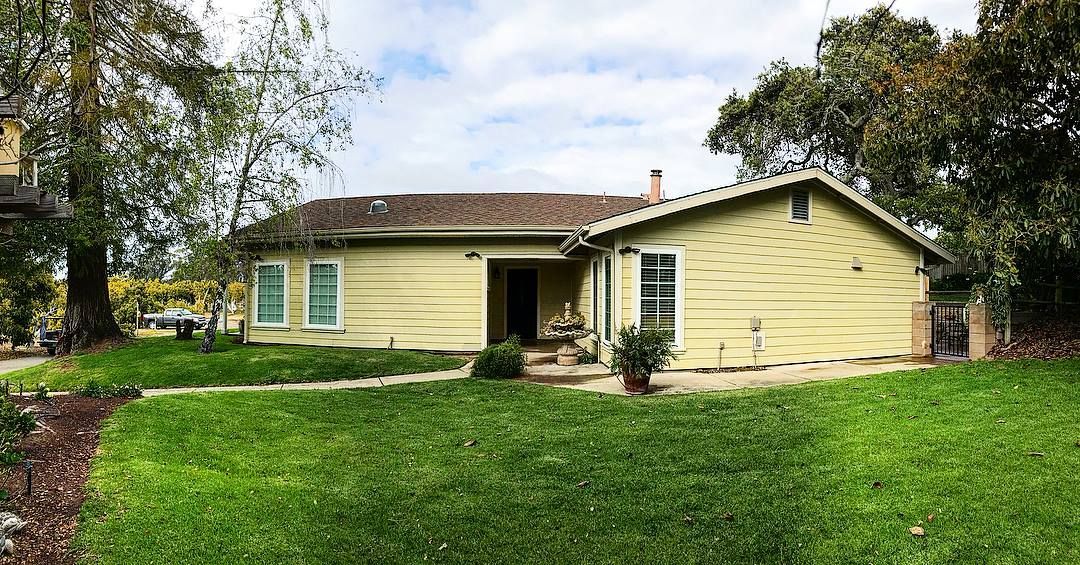 A long, freshly paved concrete driveway with orange cones leading to houses under a blue sky.