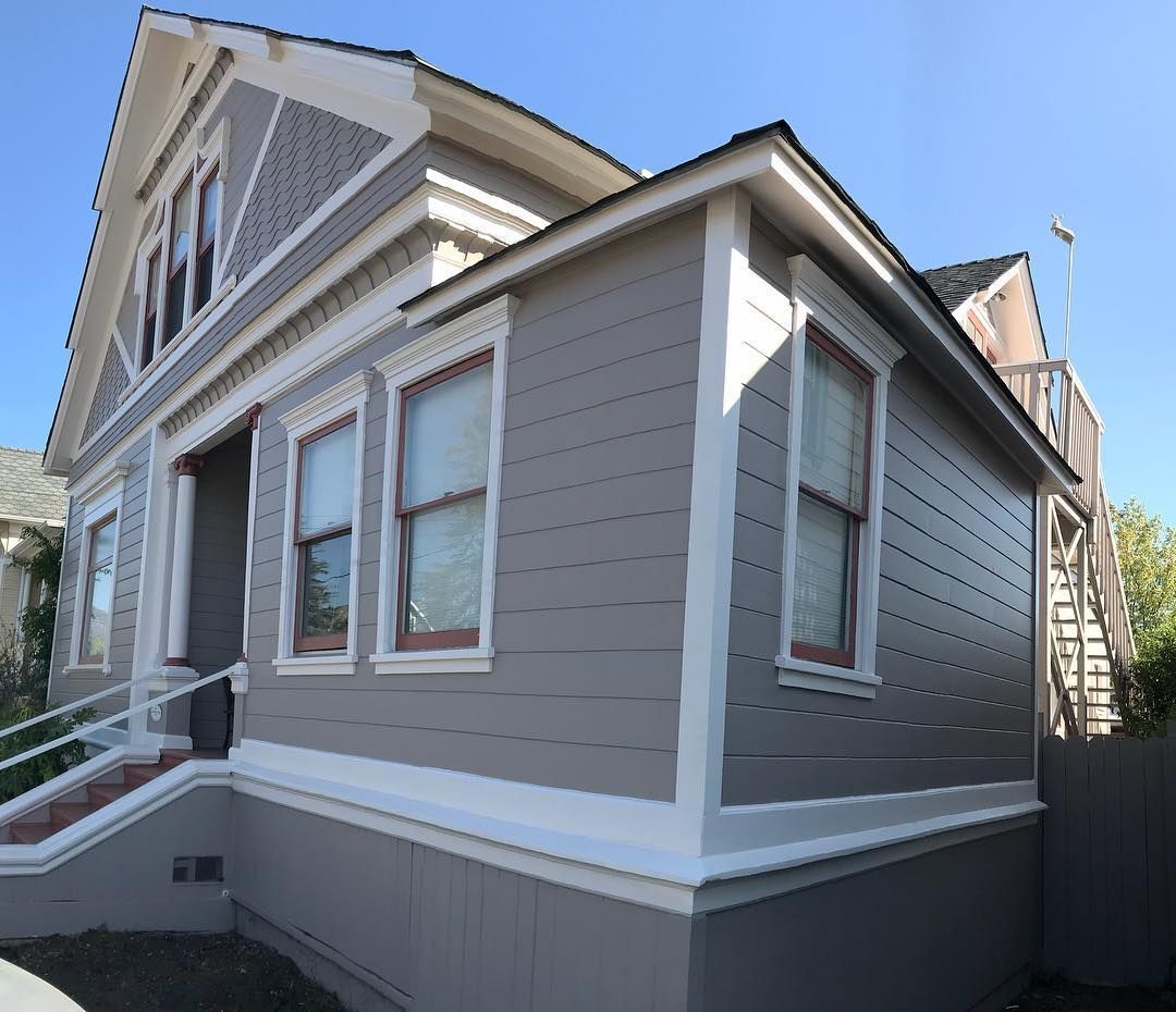Gray Victorian house with white trim, three front windows, and a side addition.
