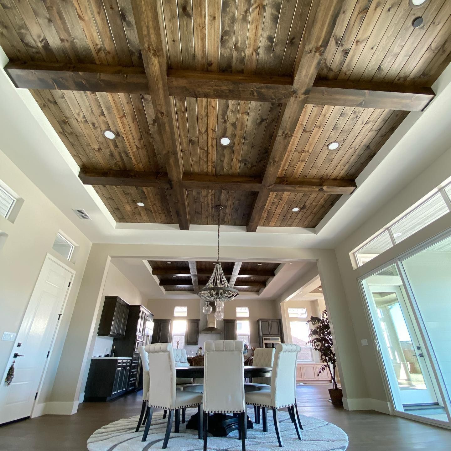 Dining room with wooden beam ceiling and chandelier above a table with six chairs.