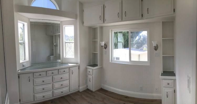 Kitchen with wooden ceiling beams, pendant lights, and island overlooking a sunny living space.