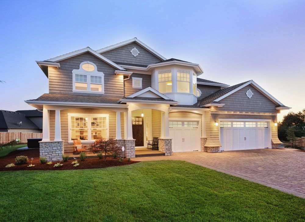 Two-story house with tan siding, white trim, and a manicured lawn. Dusk lighting.