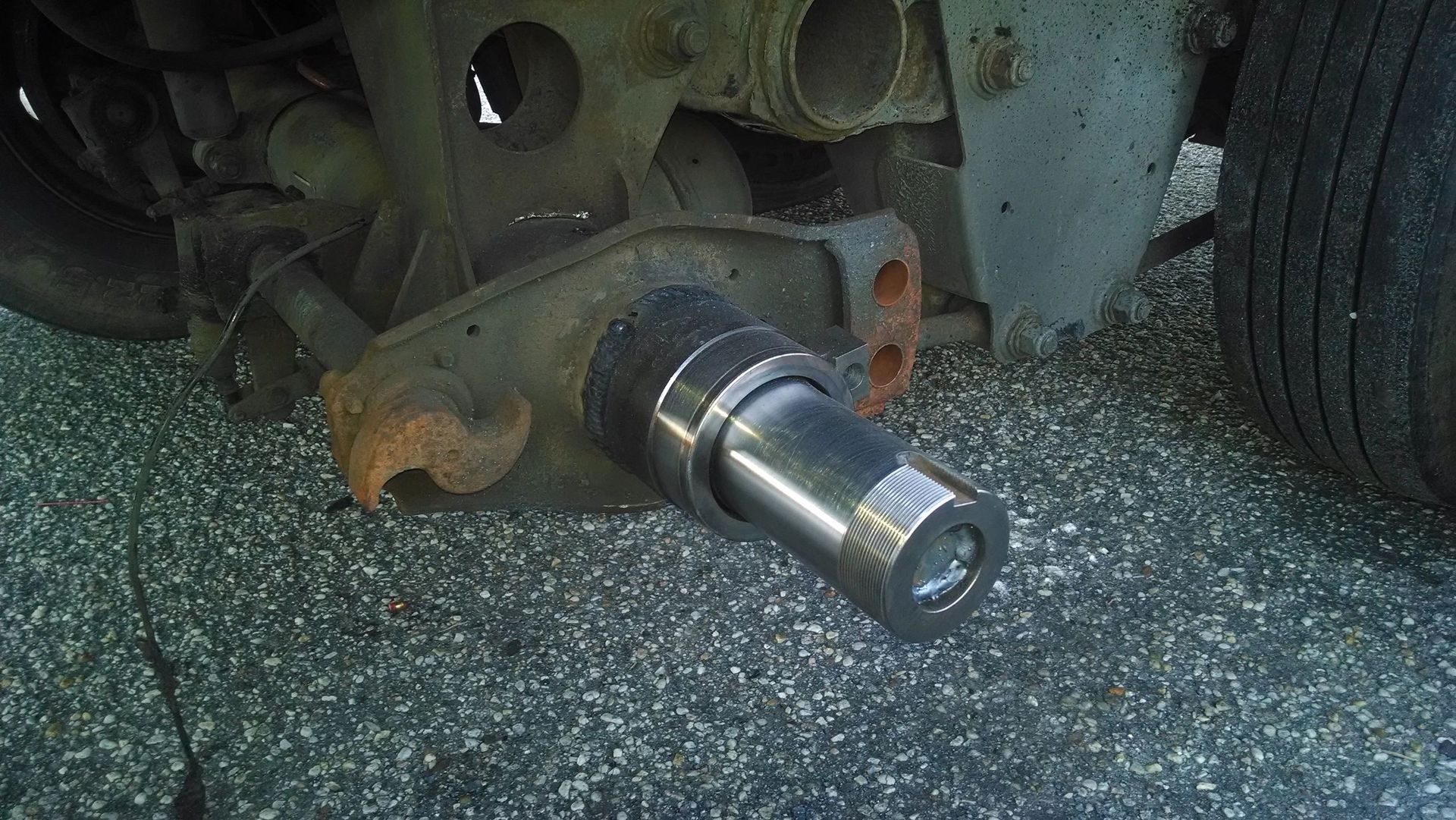 A close up of a metal object on the ground next to a car.