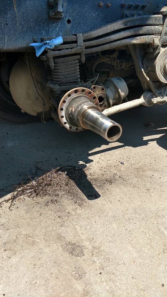 A truck with a broken exhaust pipe is parked on the side of the road.