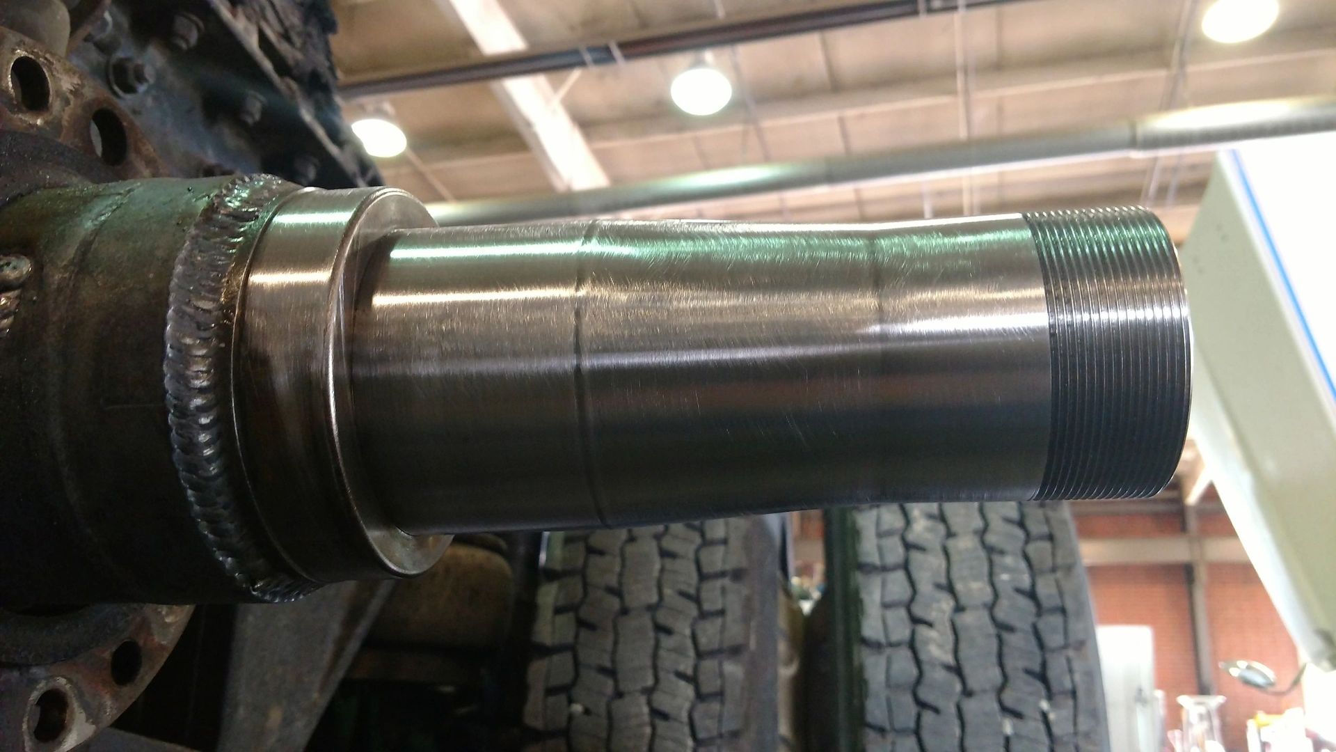 A large metal pipe is sitting on top of a tire in a garage.