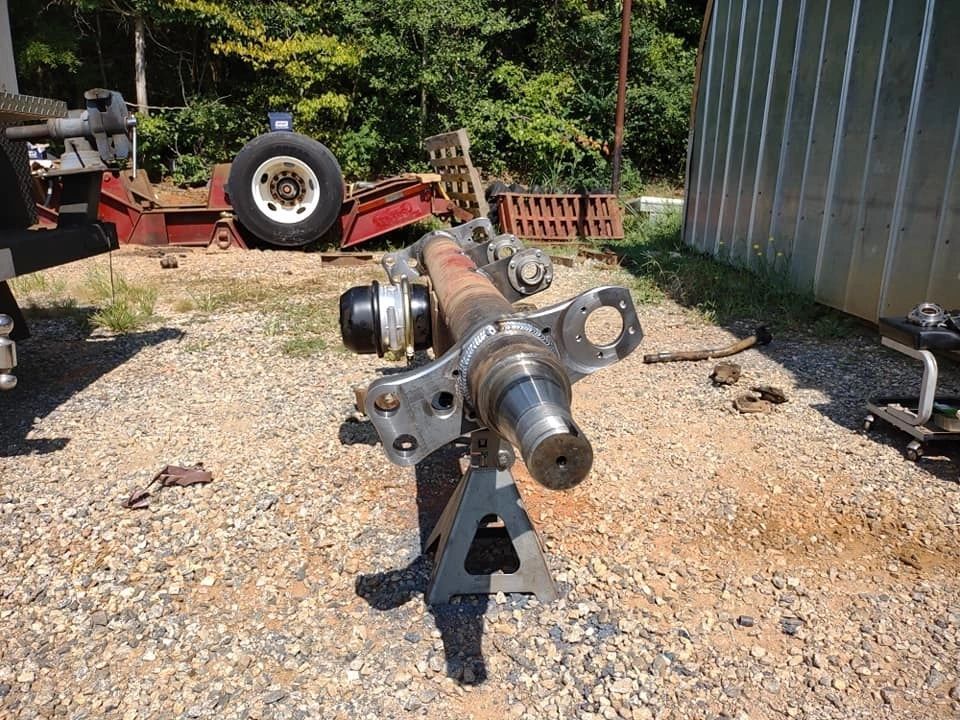 A piece of metal is sitting on a metal stand in a gravel area.