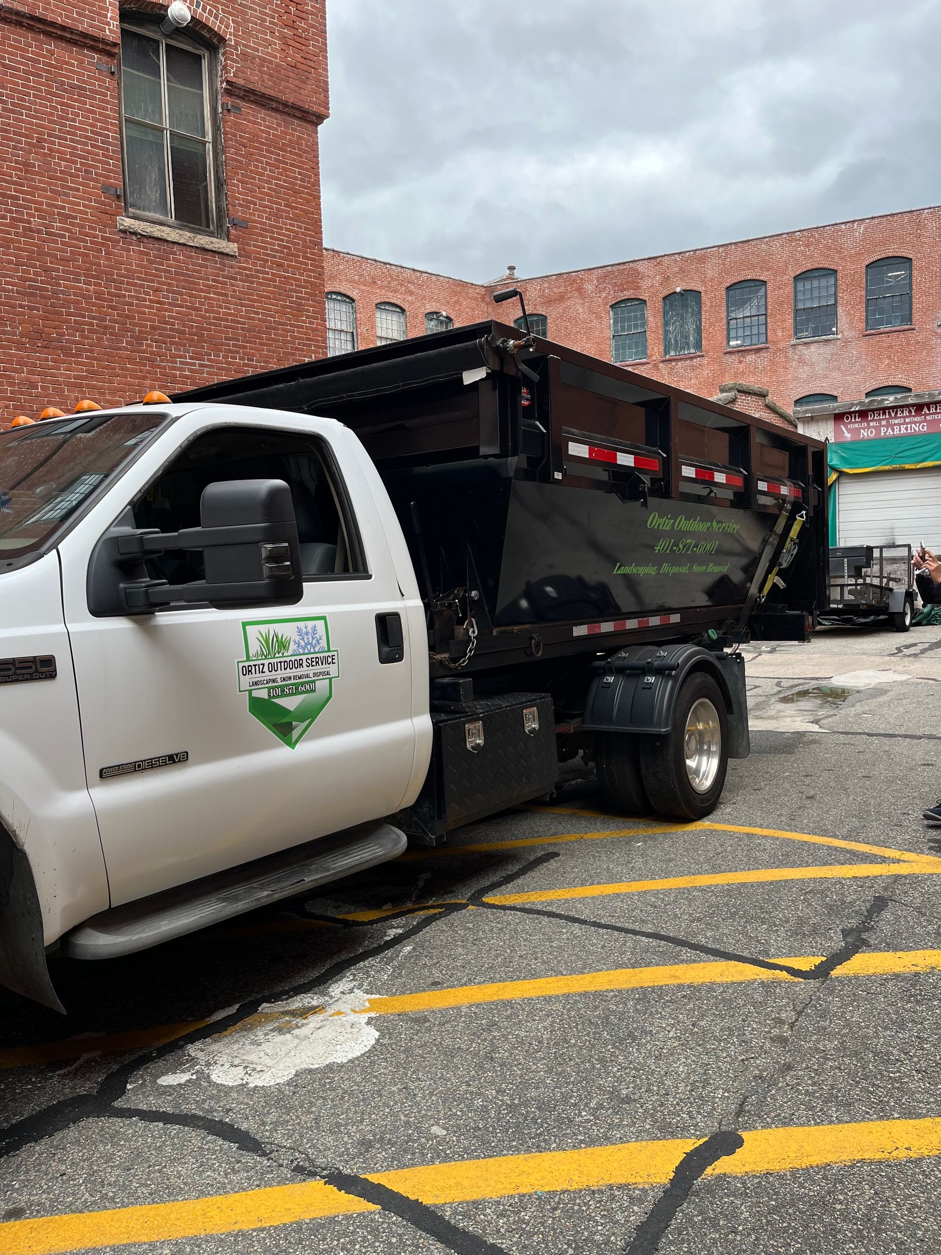 A dump truck is parked in a parking lot in front of a brick building.