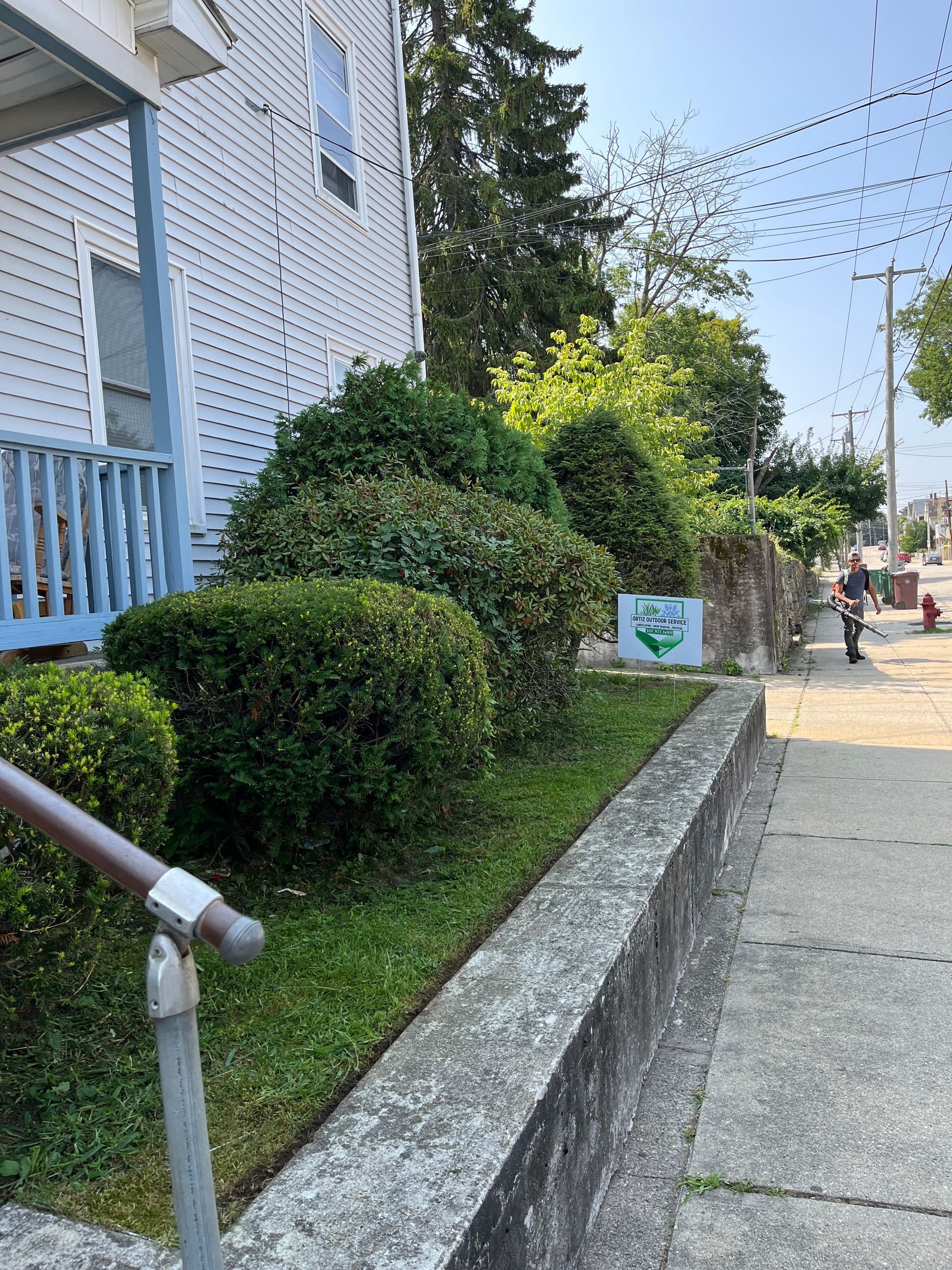 A man is riding a motorcycle down a sidewalk next to a house.