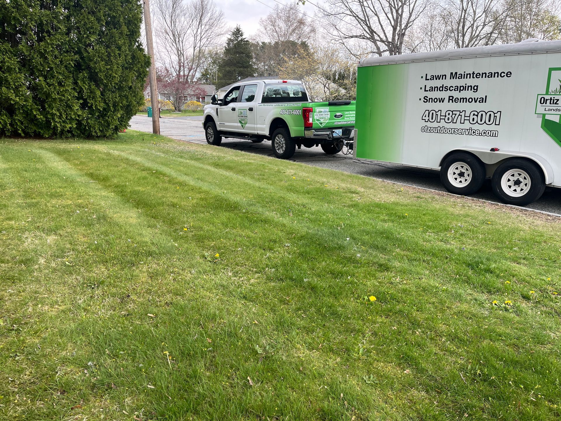 A truck and trailer are parked in a lush green field.
