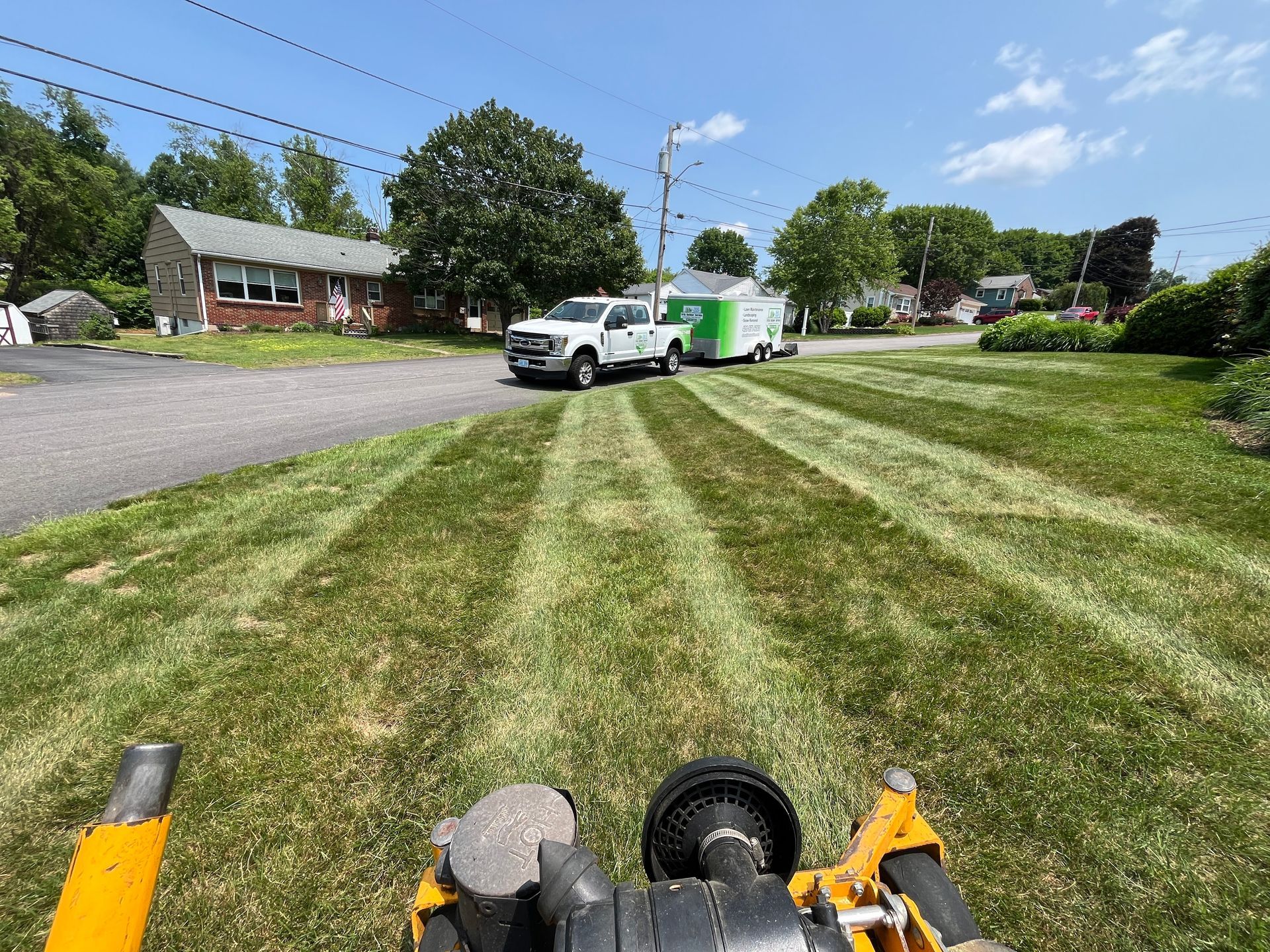 A lawn mower is cutting a lush green lawn.