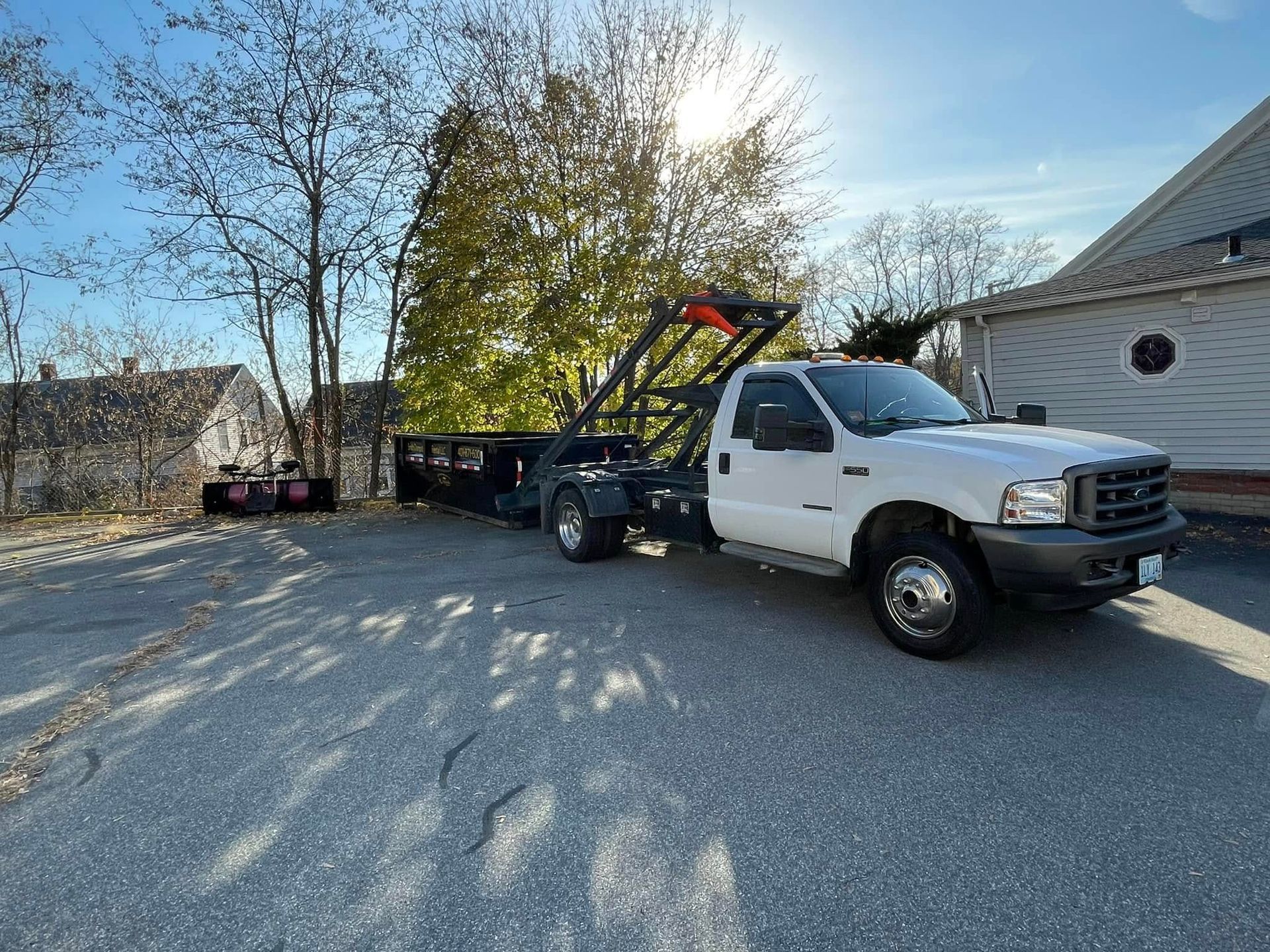 A white dump truck is parked in a parking lot next to a house.