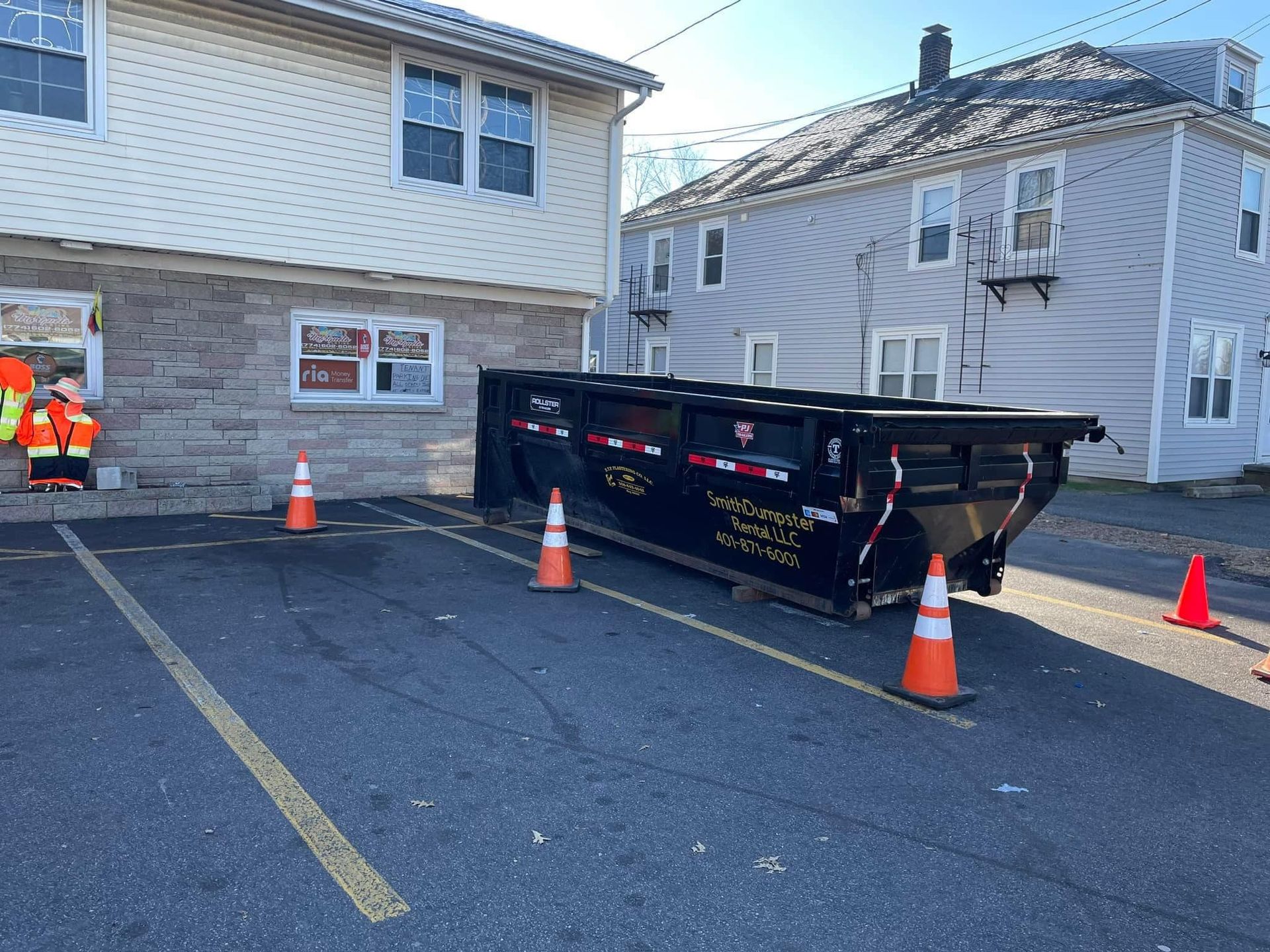 A dumpster is parked in a parking lot in front of a building.