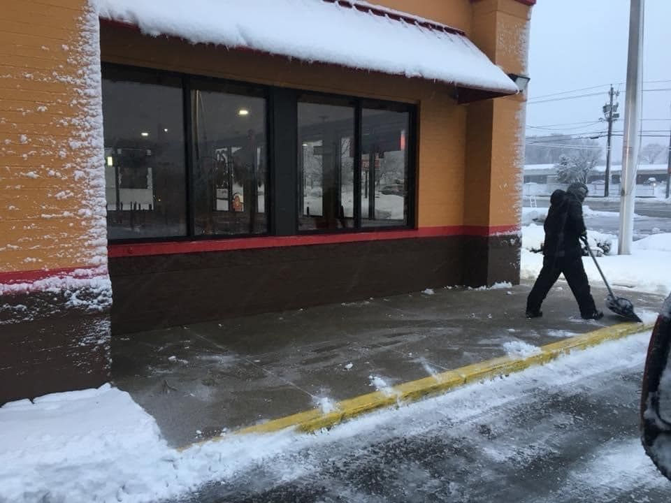 A man is shoveling snow outside of a building