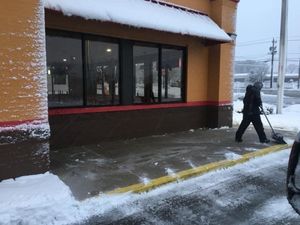 A man is shoveling snow outside of a building