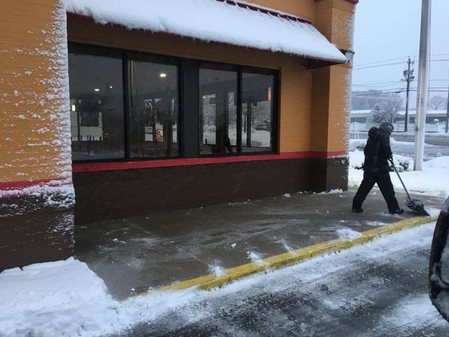 A man is shoveling snow outside of a building