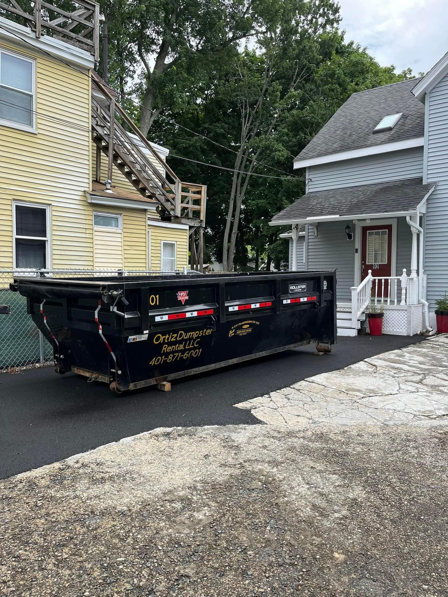 A dumpster is parked in front of a house.