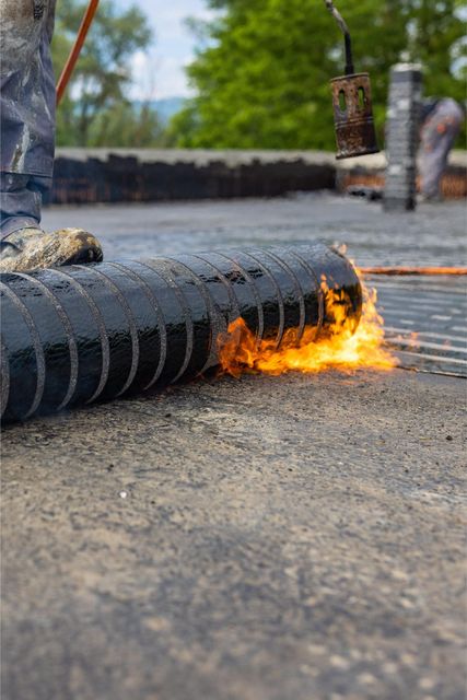 Burning hose on pavement with flames and smoke near a construction site