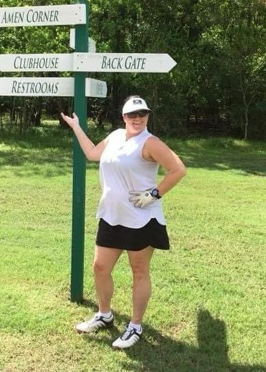 A woman is standing in front of a sign that says amen corner clubhouse restrooms and back gate