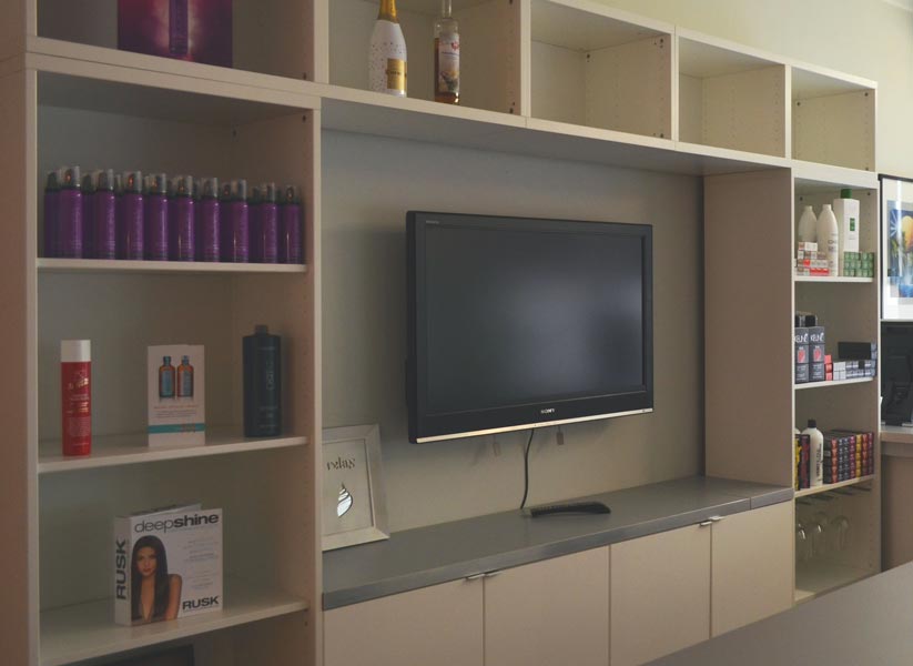 A large flat screen tv is mounted on a wall surrounded by shelves