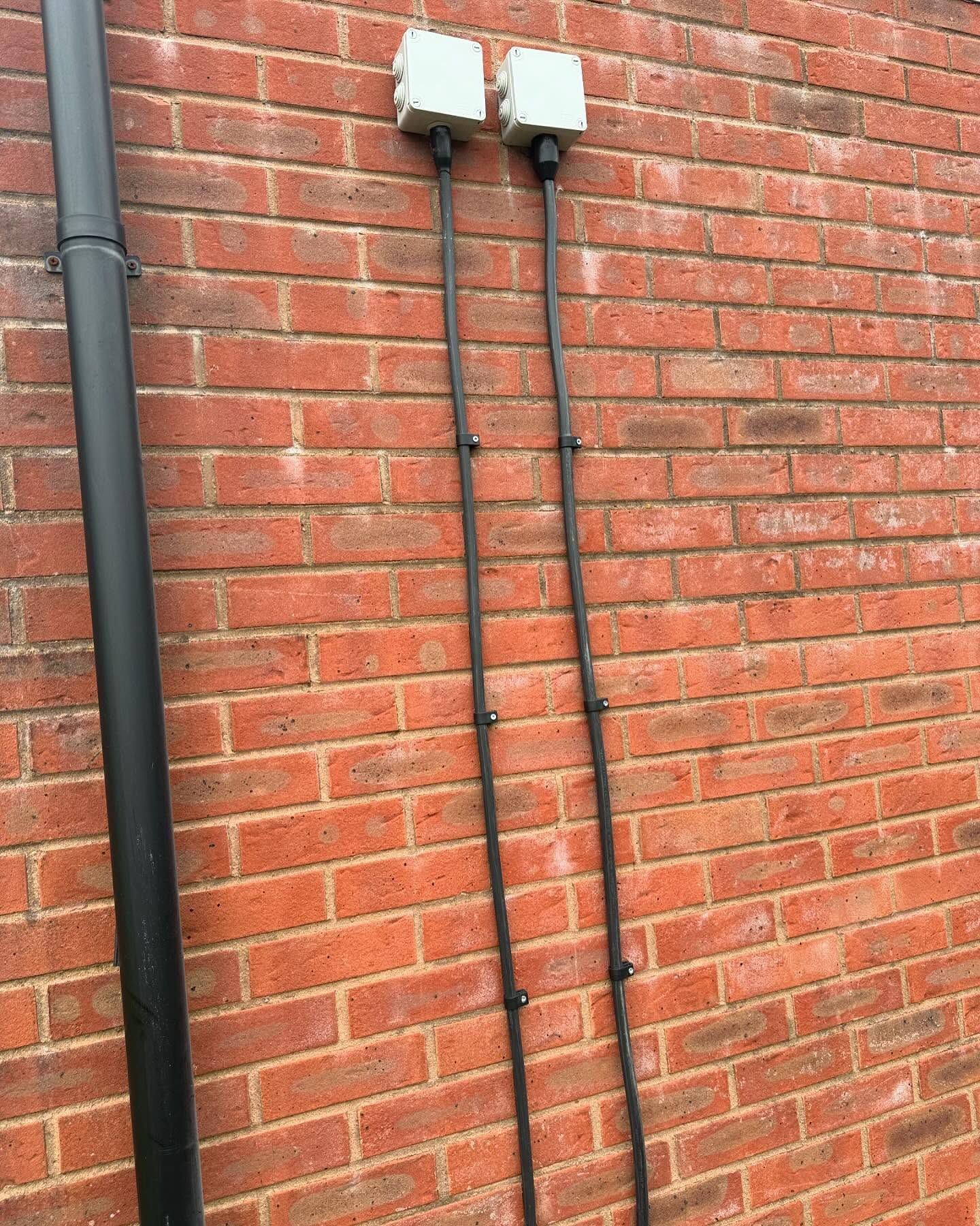 A brick wall with a black pipe and two lights on it.