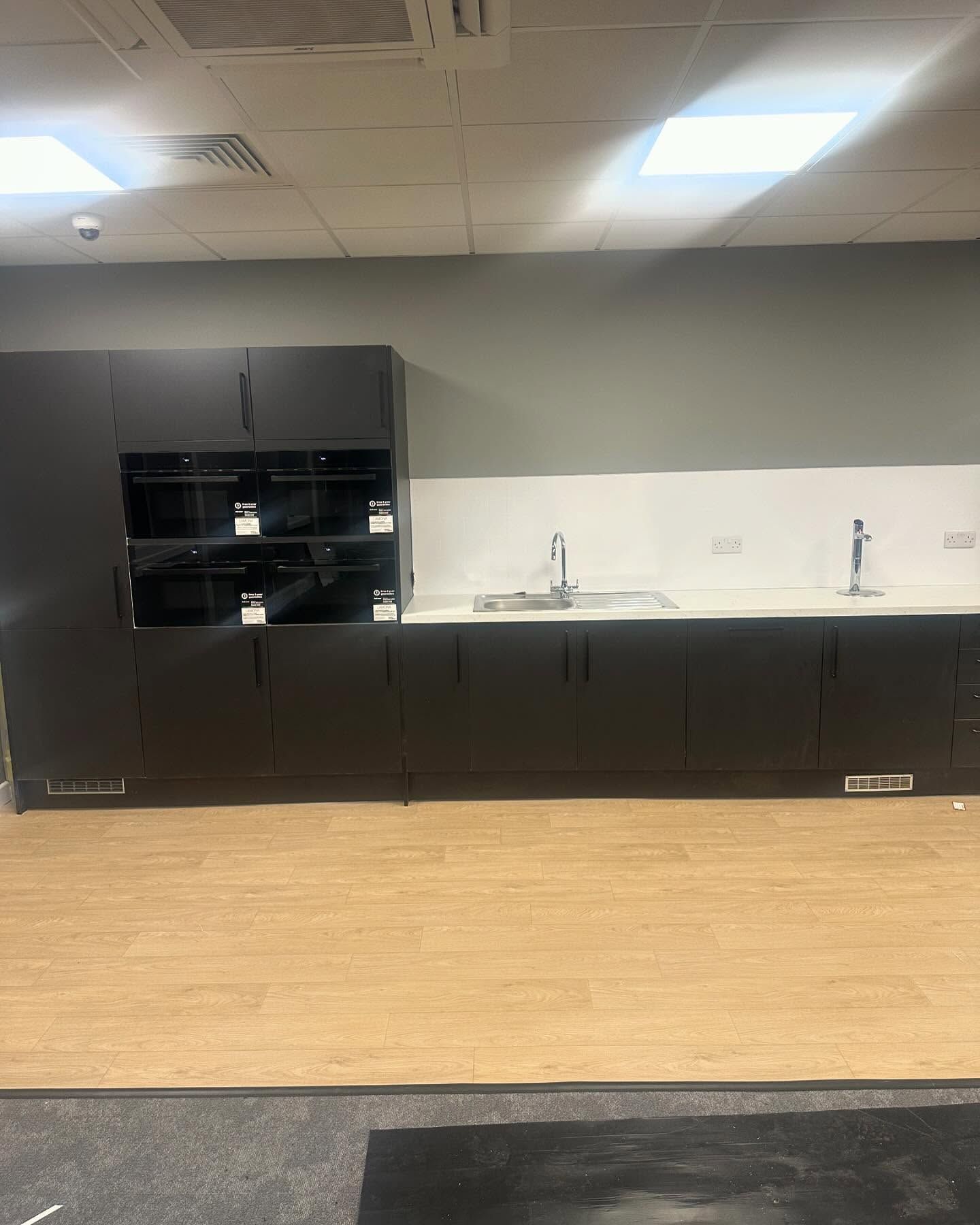 A kitchen with black cabinets , a sink , and a microwave.