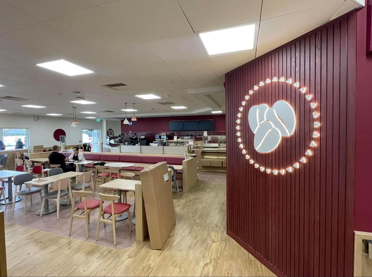 A restaurant with tables and chairs and a logo on the wall.