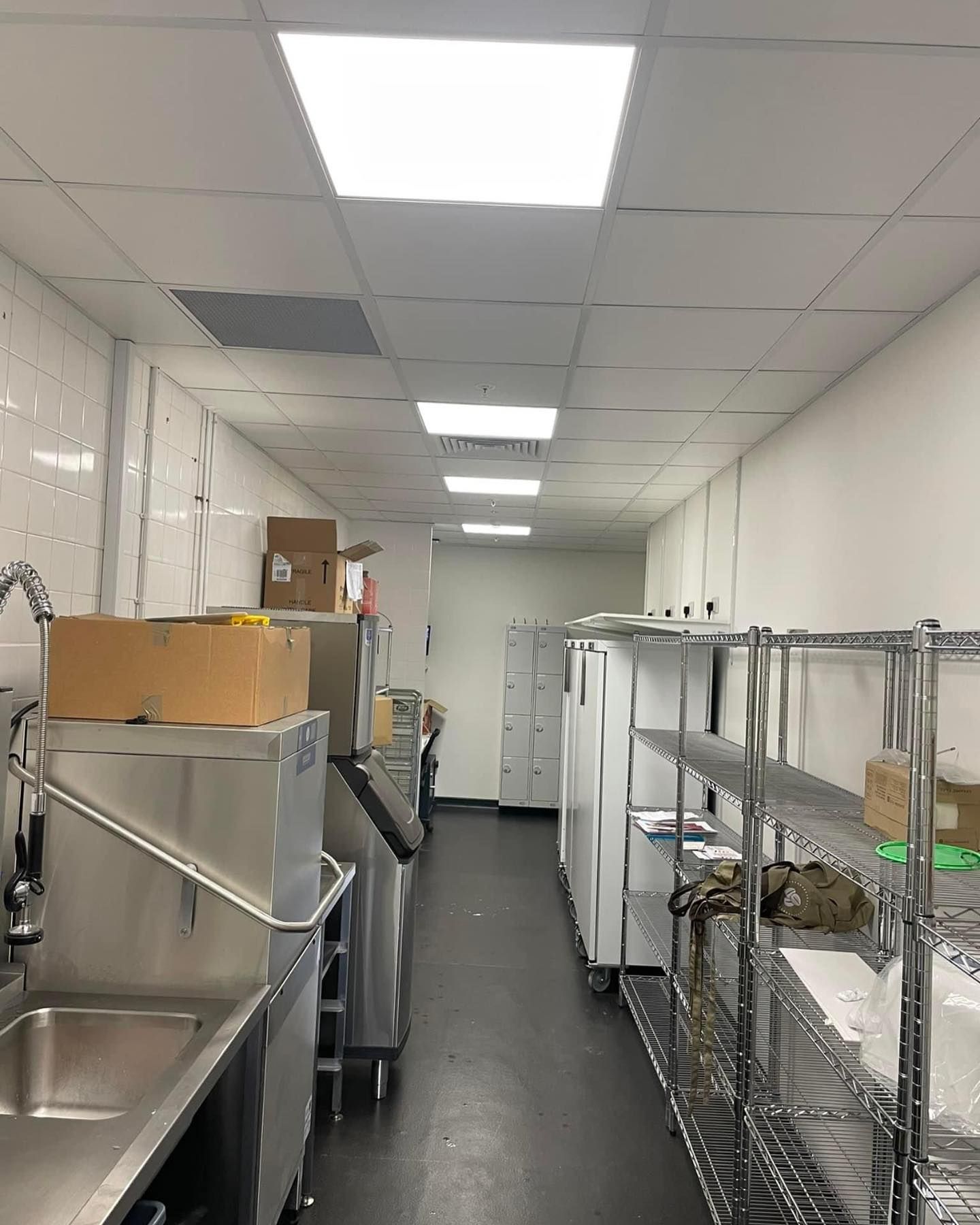 A long hallway in a kitchen with a sink and shelves.