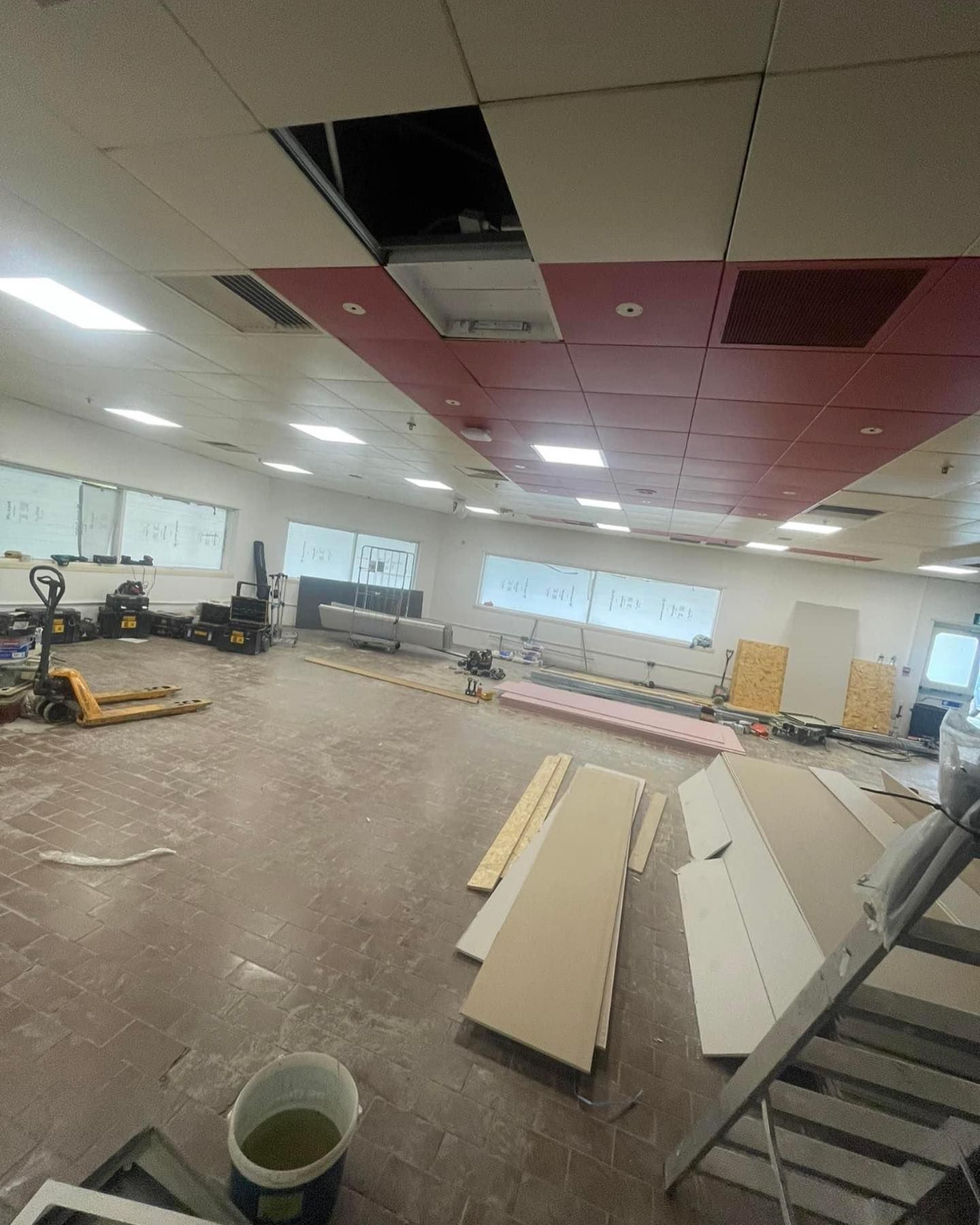 A large room with a red and white ceiling is being remodeled.