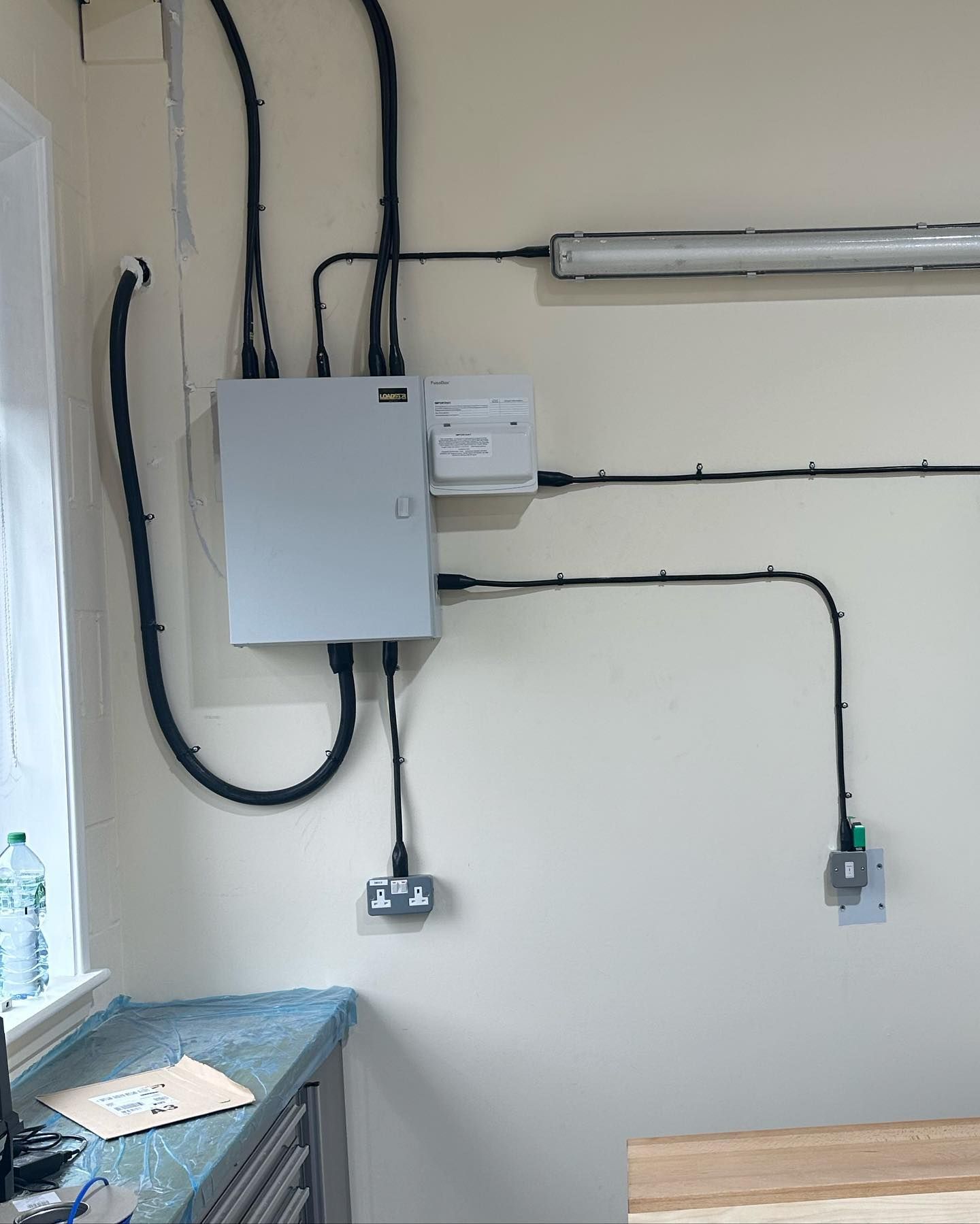 A white box is hanging on a wall next to a window.