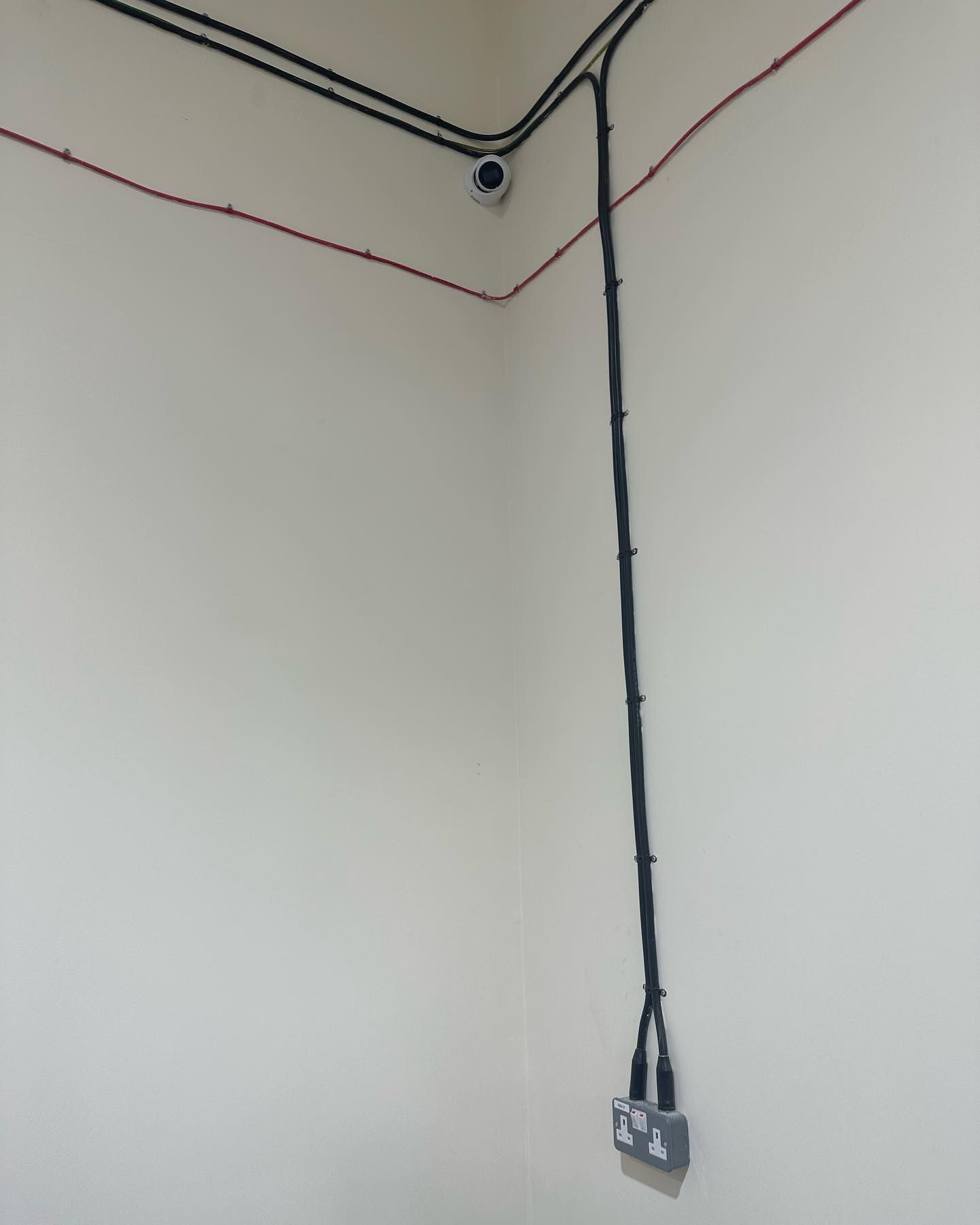 A corner of a room with electrical wires hanging from the ceiling