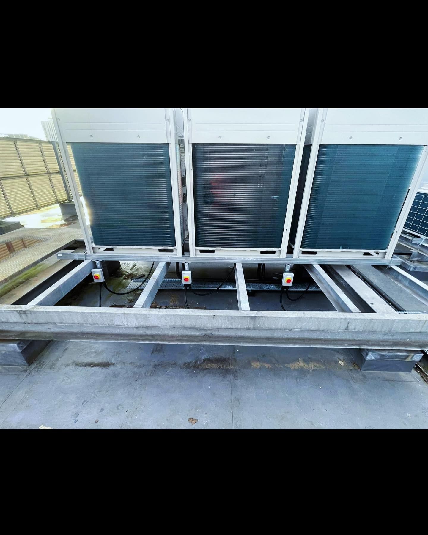 A group of air conditioners are sitting on top of a roof.