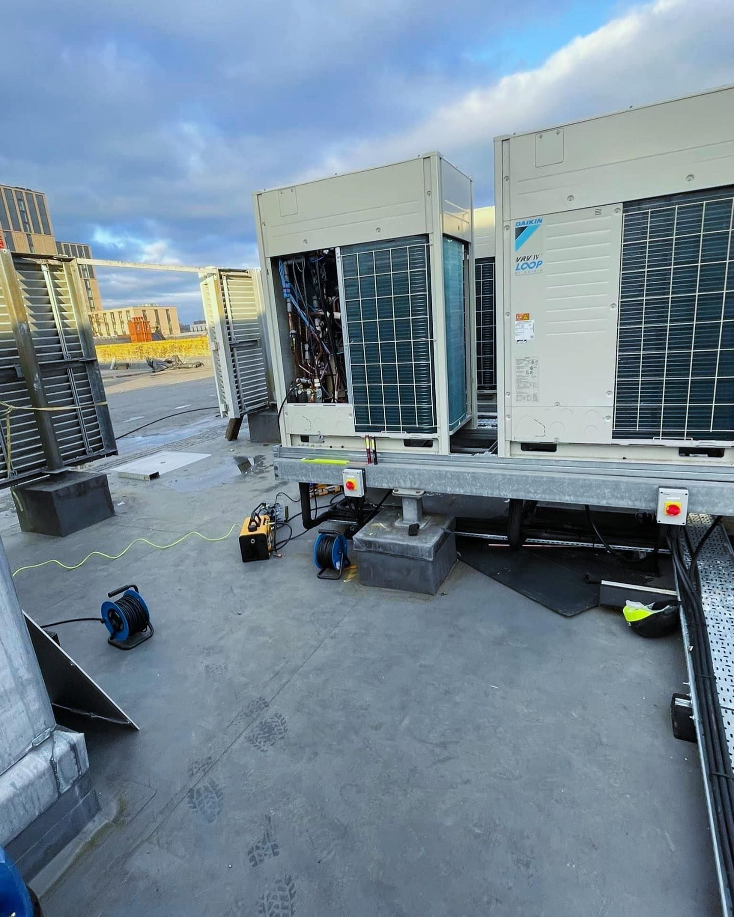 A group of air conditioners are sitting on top of a concrete roof.