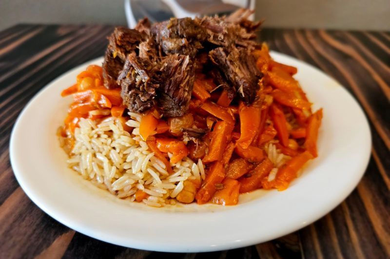 A white plate topped with rice and carrots on a wooden table.