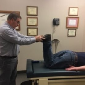 A man is stretching another man 's leg on a table