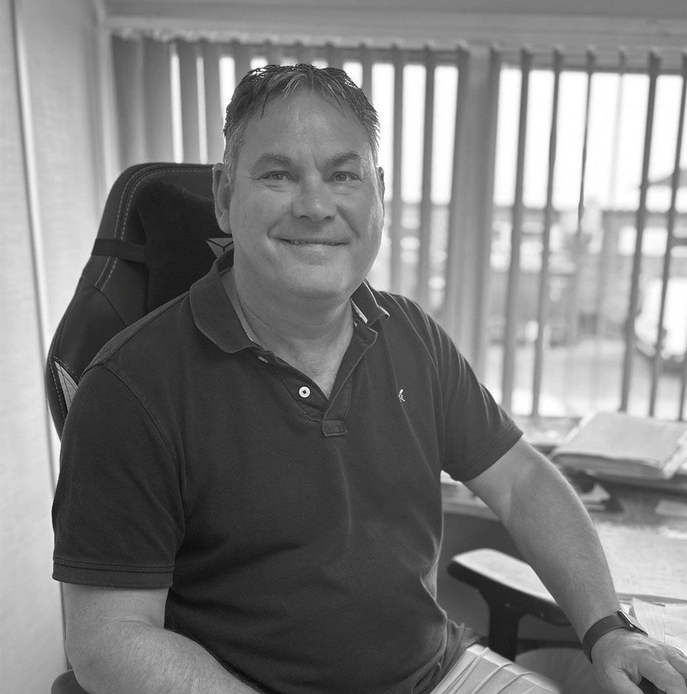 A man is sitting in an office chair in front of a window.