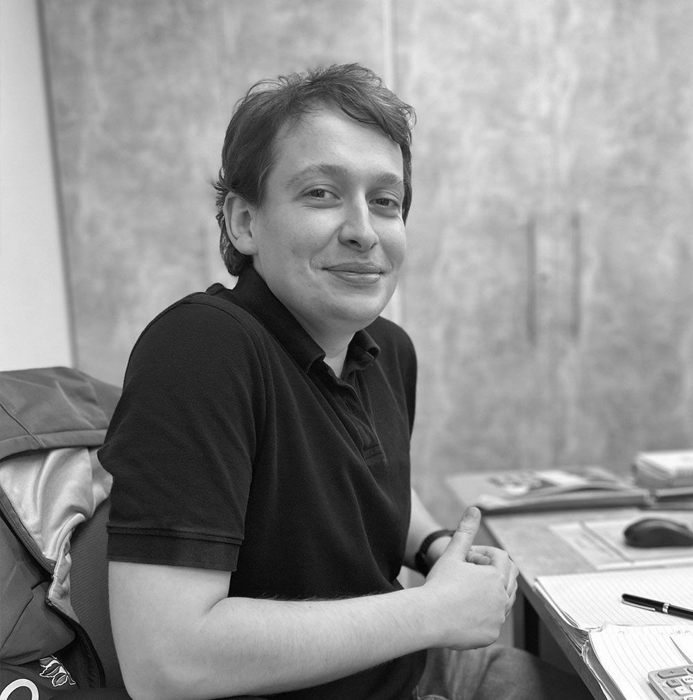 A man in a black shirt is smiling in a black and white photo