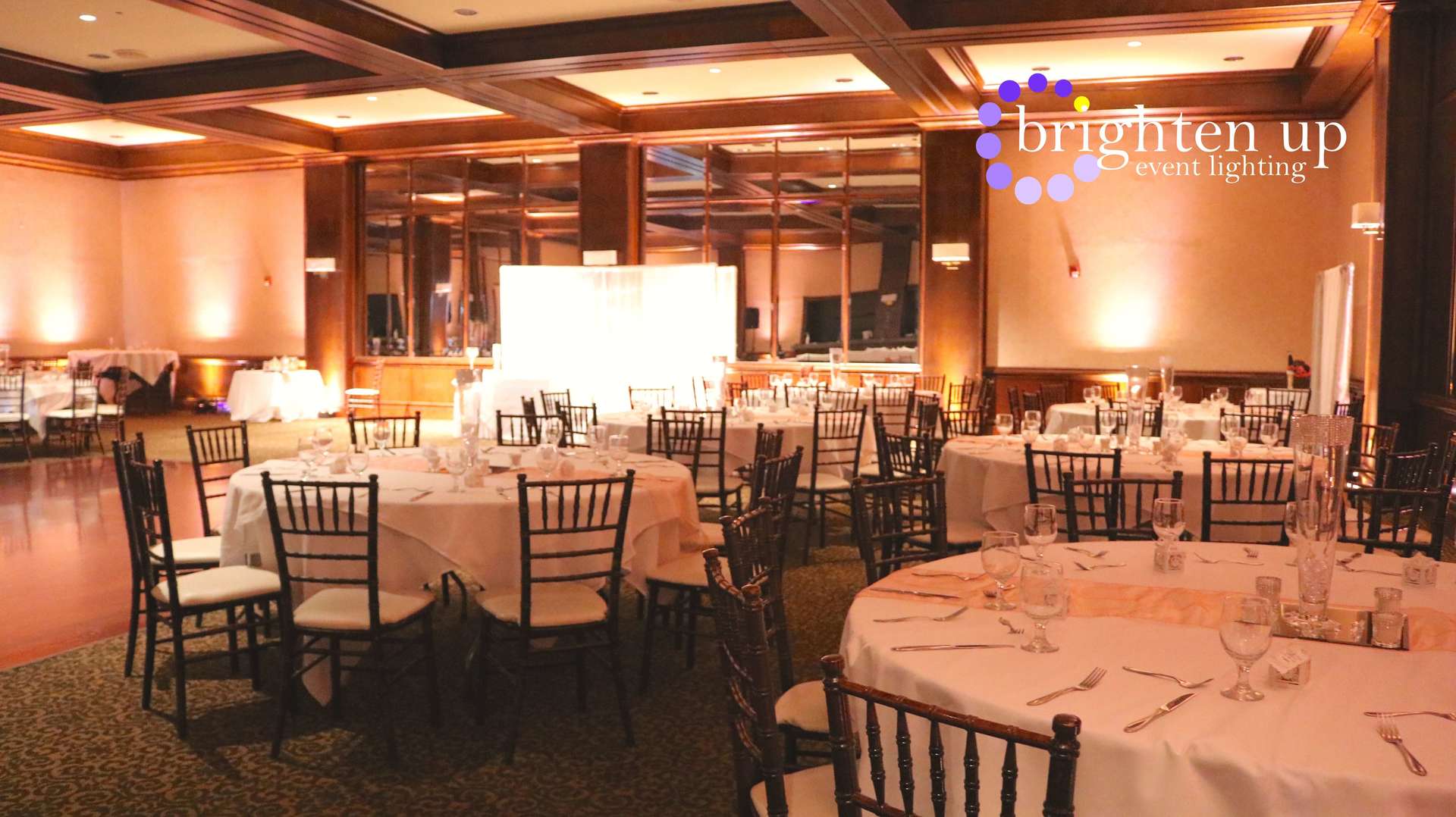 A large room with tables and chairs set up for a wedding reception