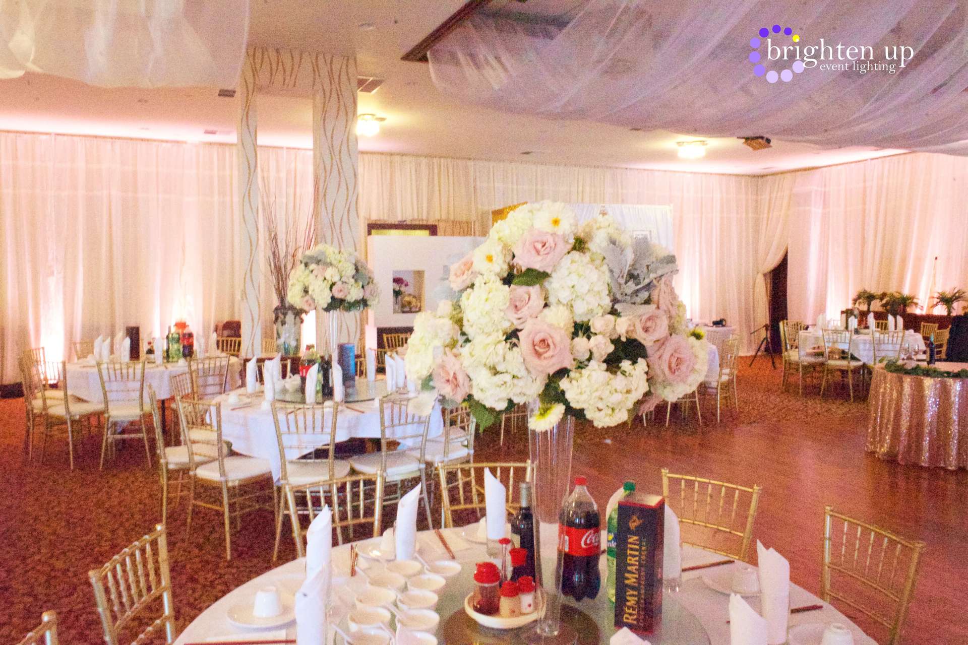 A large room with tables and chairs set up for a wedding reception