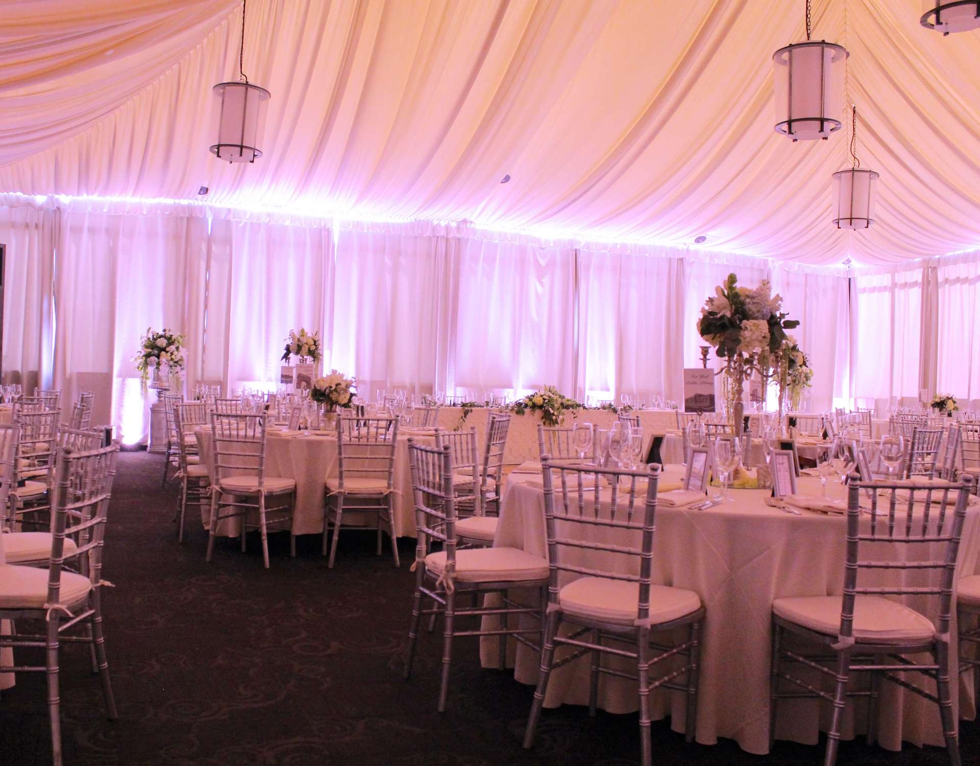 A large room with tables and chairs set up for a wedding reception.