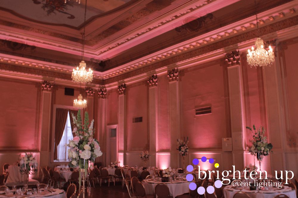 A large room with tables and chairs and pink lights on the walls.