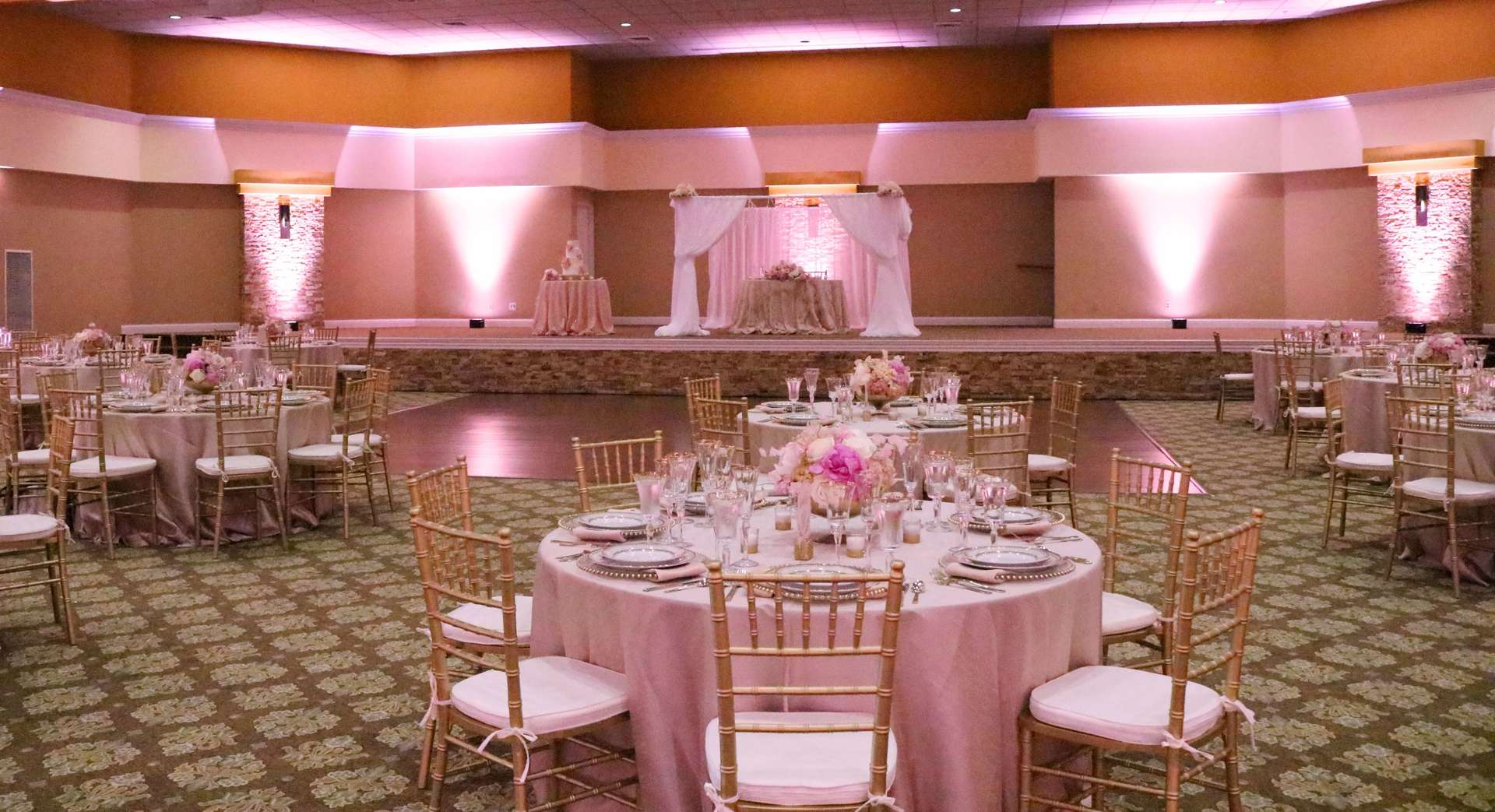 A large room with tables and chairs set up for a wedding reception.