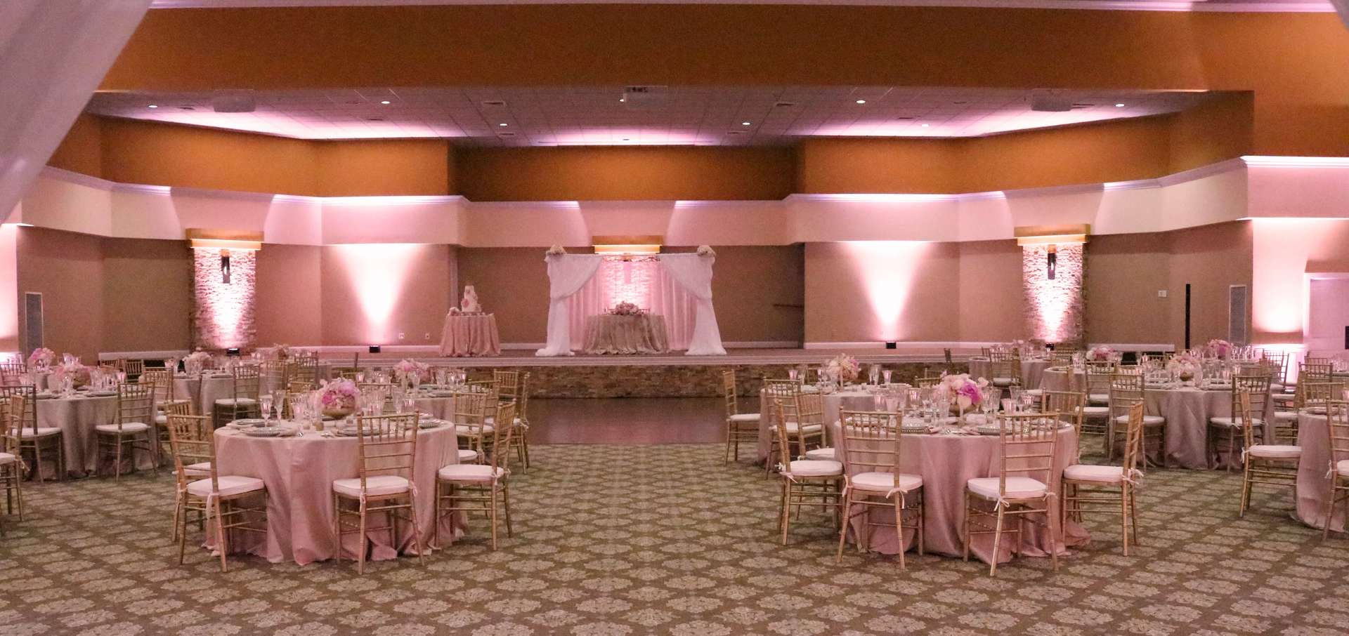 A large room with tables and chairs set up for a wedding reception